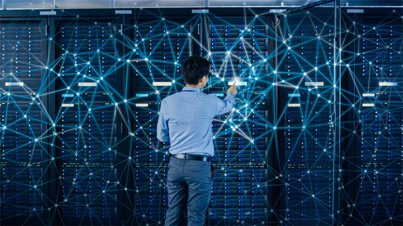 Internet Web Concept. Shot In the Modern Data Center: IT Engineer Standing Beside Open Server Rack Cabinets and Touching Digital Connections on a Server.